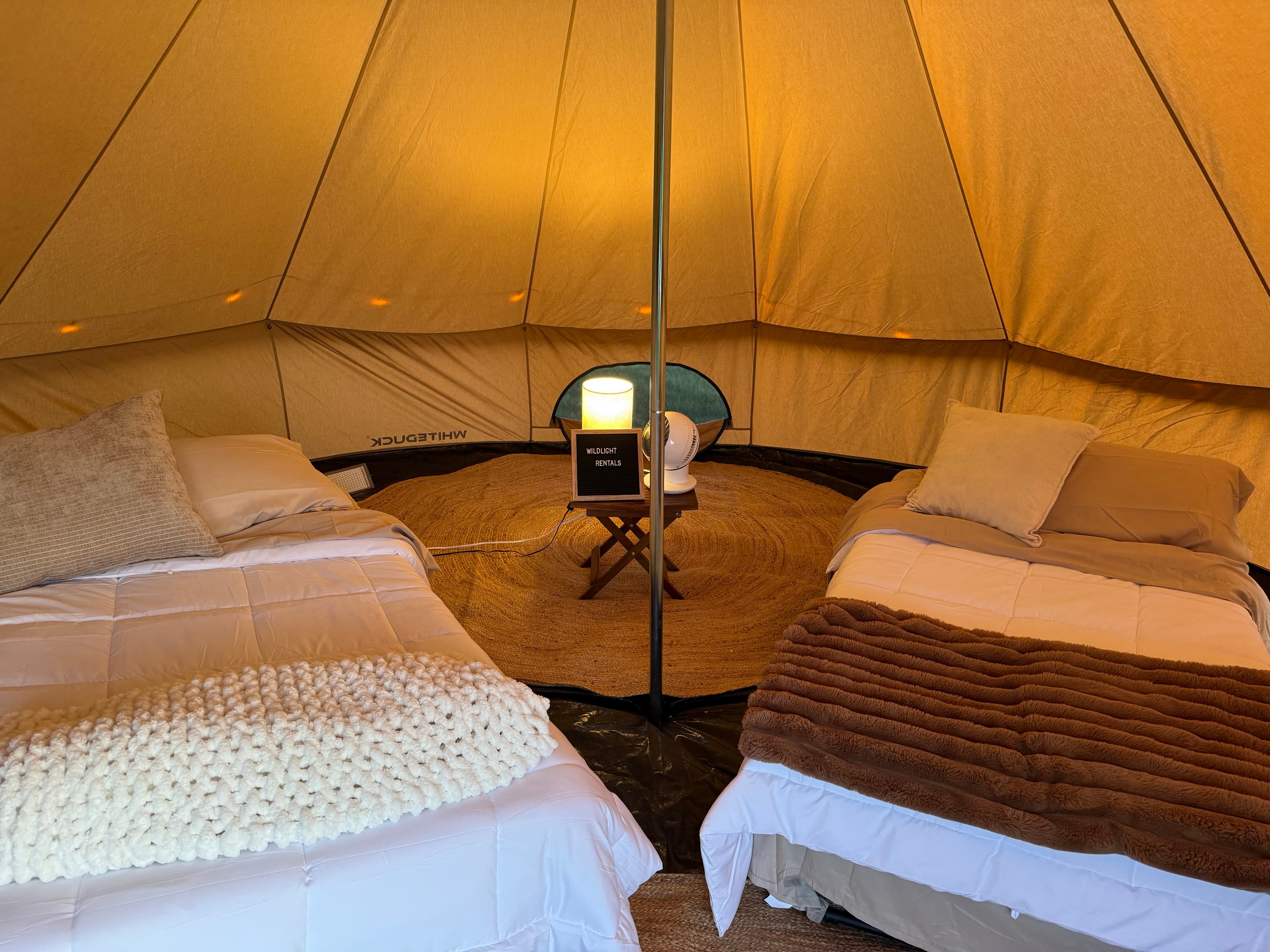 Warm ambient bell tent interior with cozy bedding