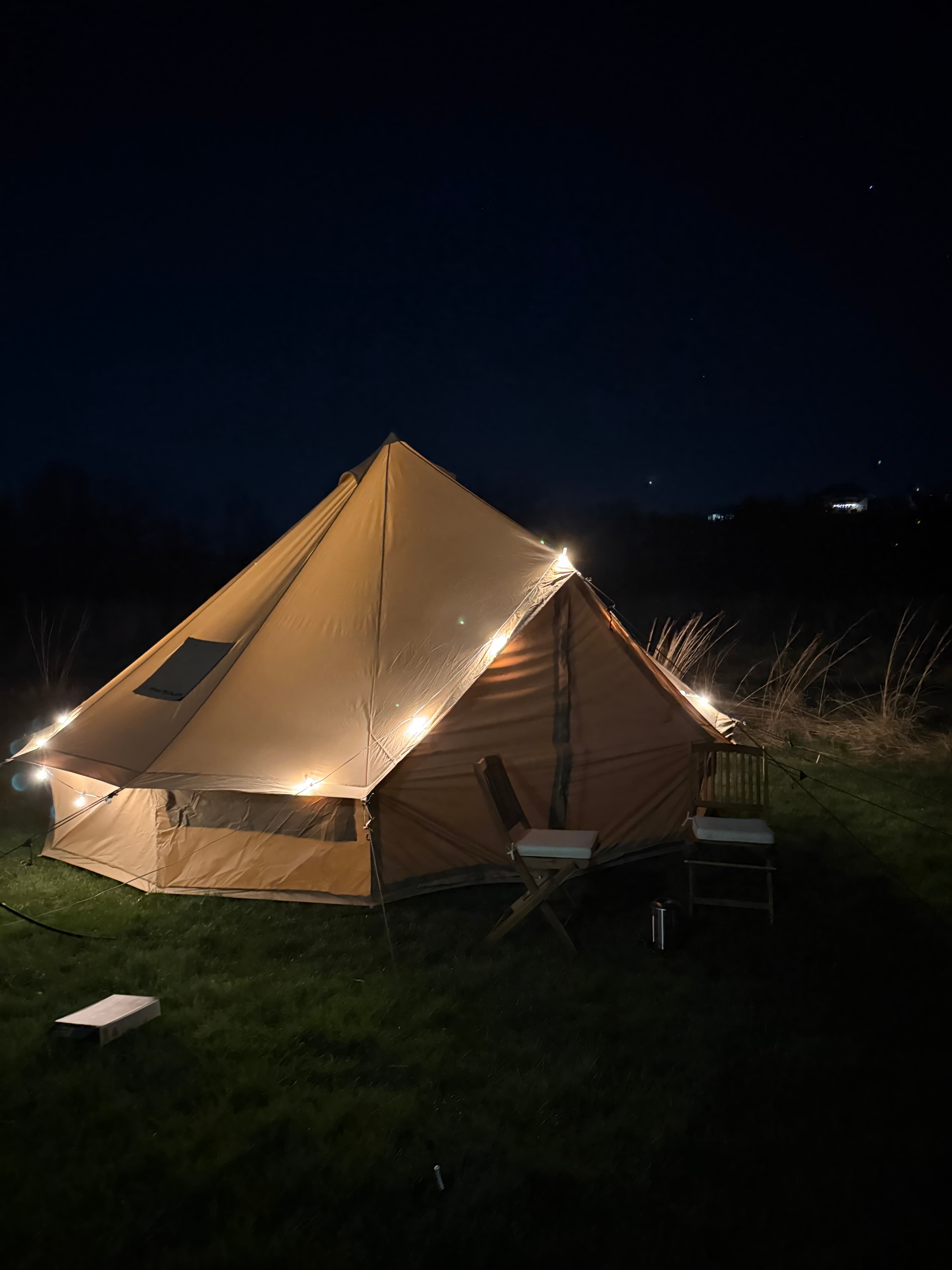 Bell tent glowing with string lights at night