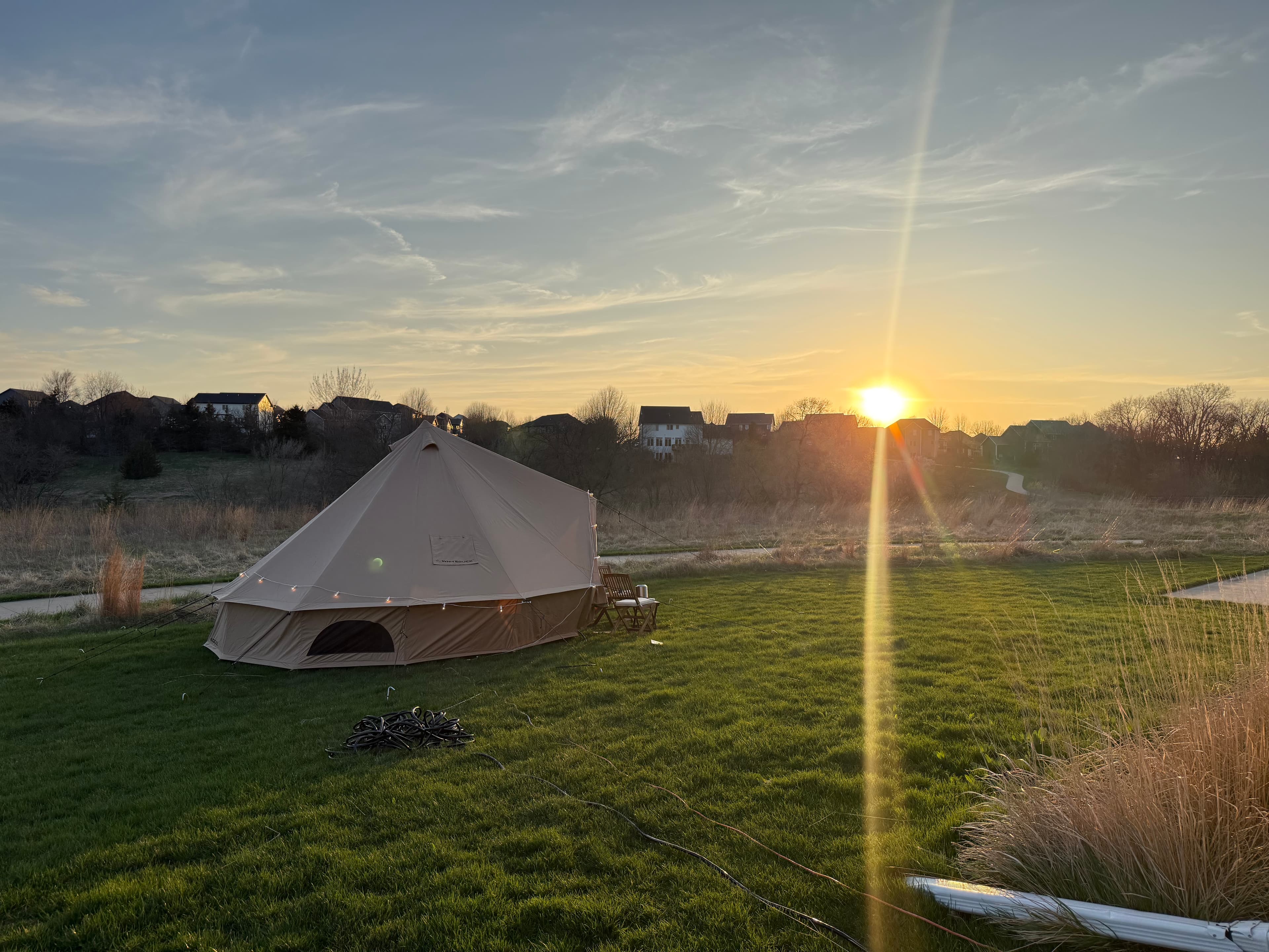 Wildlight Rentals bell tent in an open field at sunset with sun flare